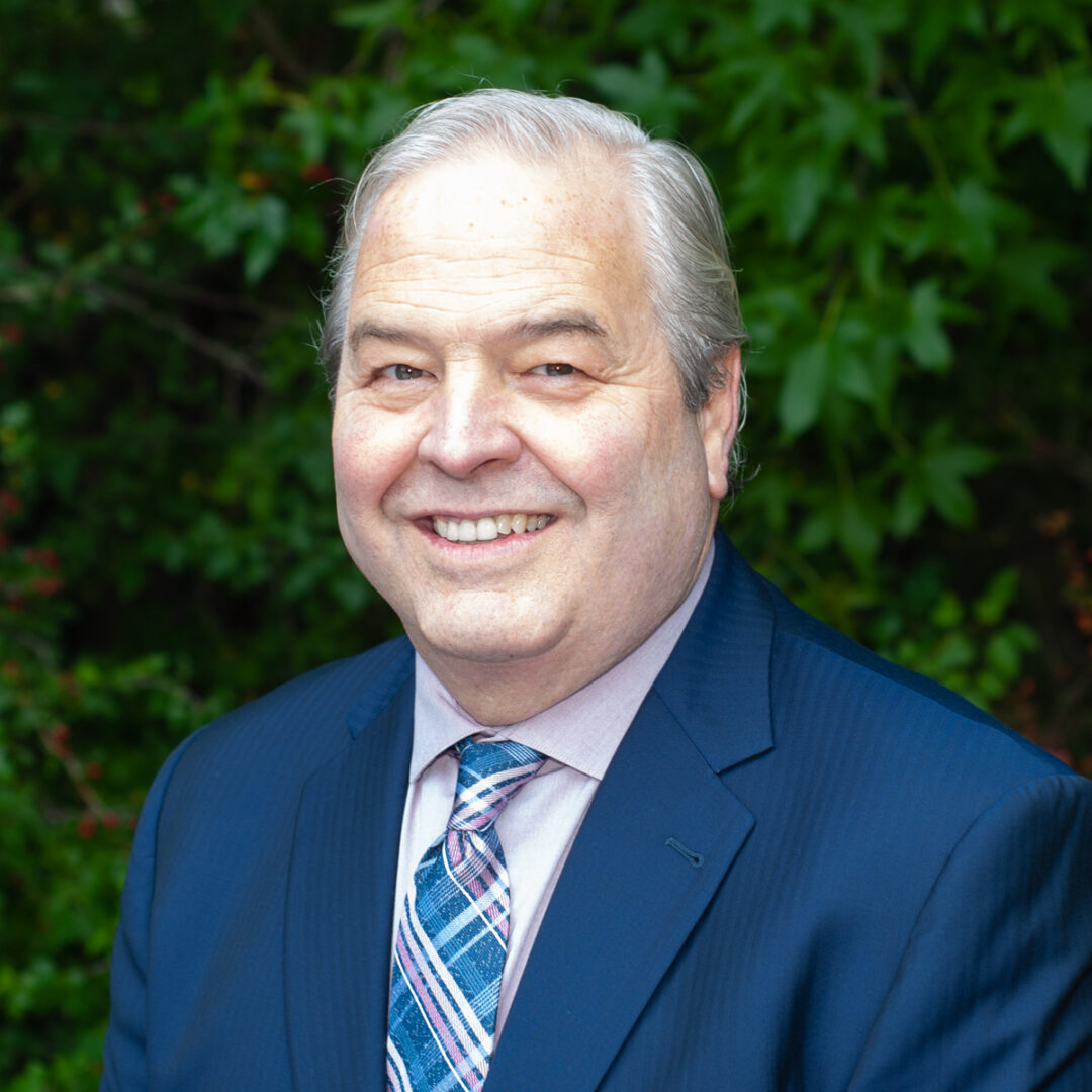 A white-haired guy in a blue suit smiling